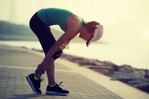 Runner stretching their leg, representing who can benefit from sports massage treatment